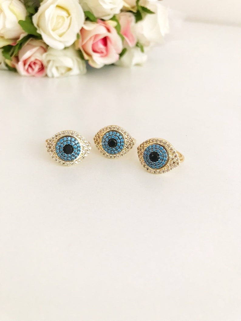 A stunning Zirconia Evil Eye Ring featuring a blue evil eye bead and sparkling zirconia stones, set in a gold adjustable band.