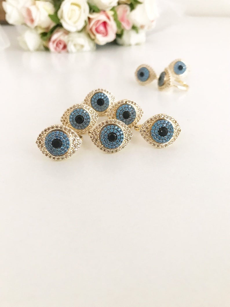 A stunning Zirconia Evil Eye Ring featuring a blue evil eye bead and sparkling zirconia stones, set in a gold adjustable band.