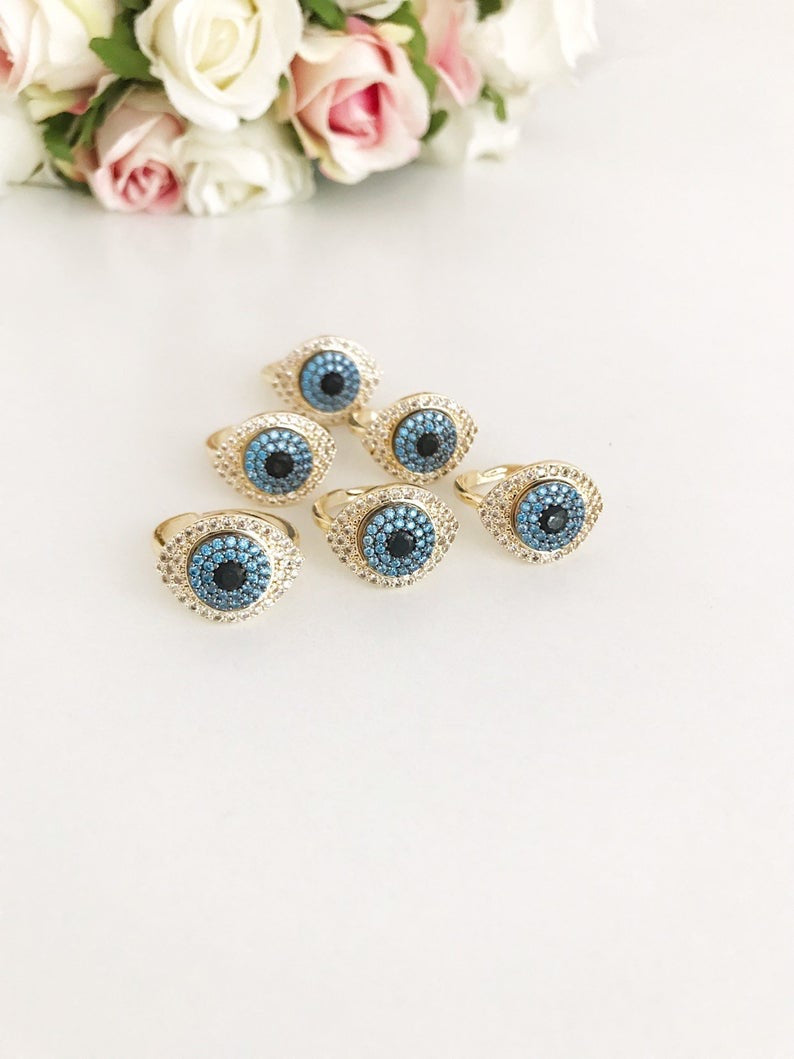 A stunning Zirconia Evil Eye Ring featuring a blue evil eye bead and sparkling zirconia stones, set in a gold adjustable band.