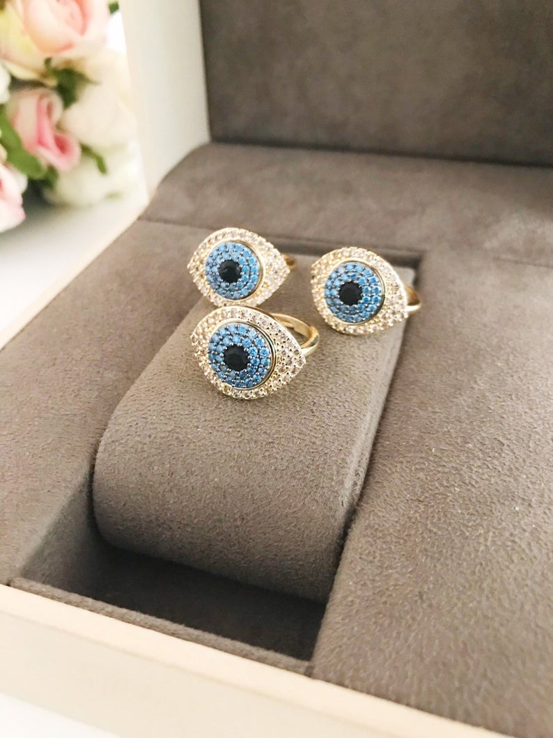 A stunning Zirconia Evil Eye Ring featuring a blue evil eye bead and sparkling zirconia stones, set in a gold adjustable band.