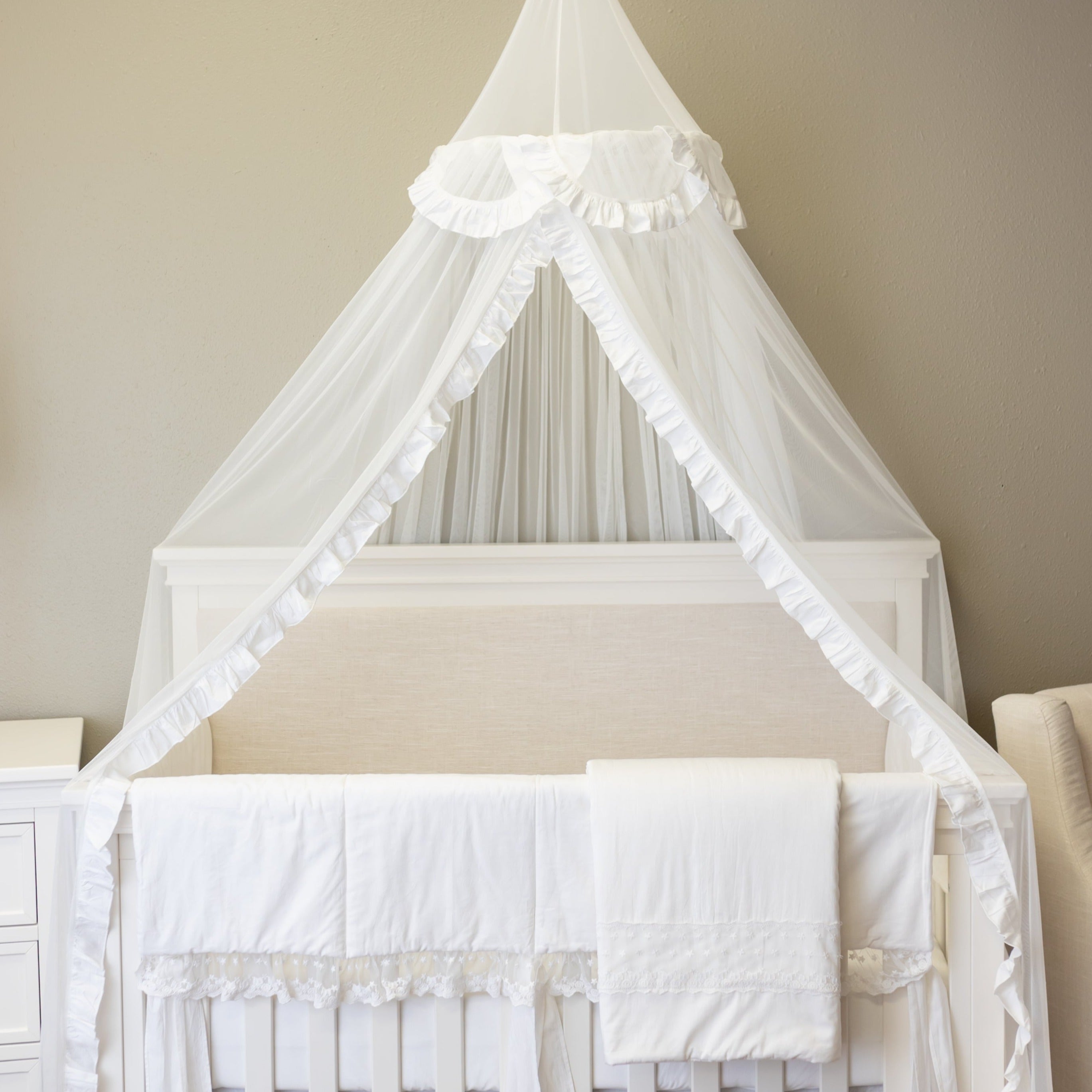 A beautiful white tulle canopy draped over a crib, creating an elegant and cozy nursery atmosphere.