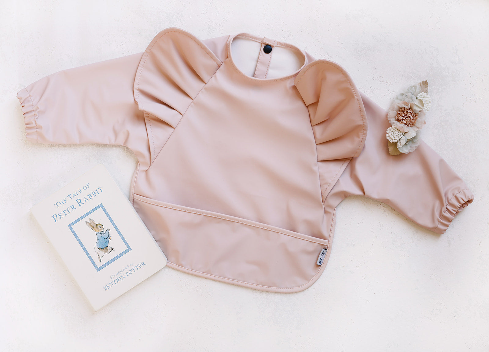 Peach Blush Long Sleeve Ruffle Angel Bib with ruffles and button closure, designed for babies aged 6-12 months, featuring a built-in pocket.