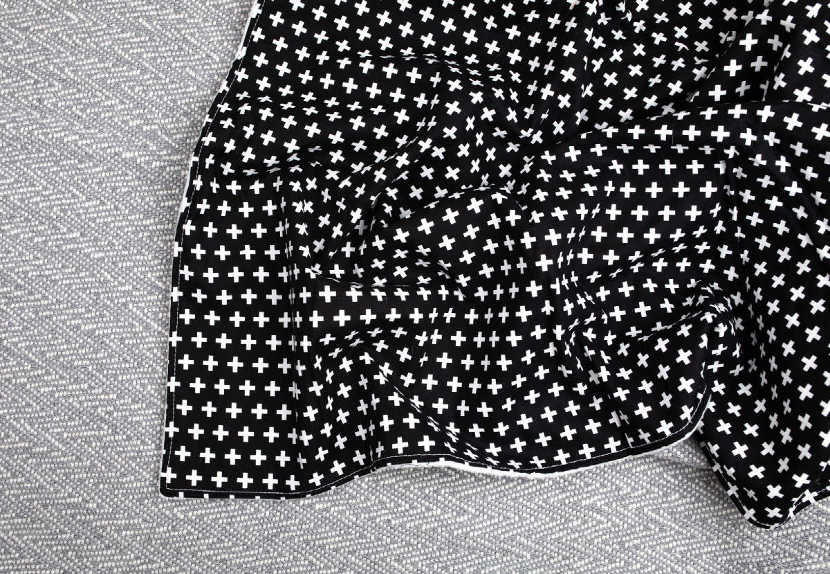 Lina Baby Blanket featuring a modern black and white swiss cross design with soft white minky backing, perfect for nurseries.