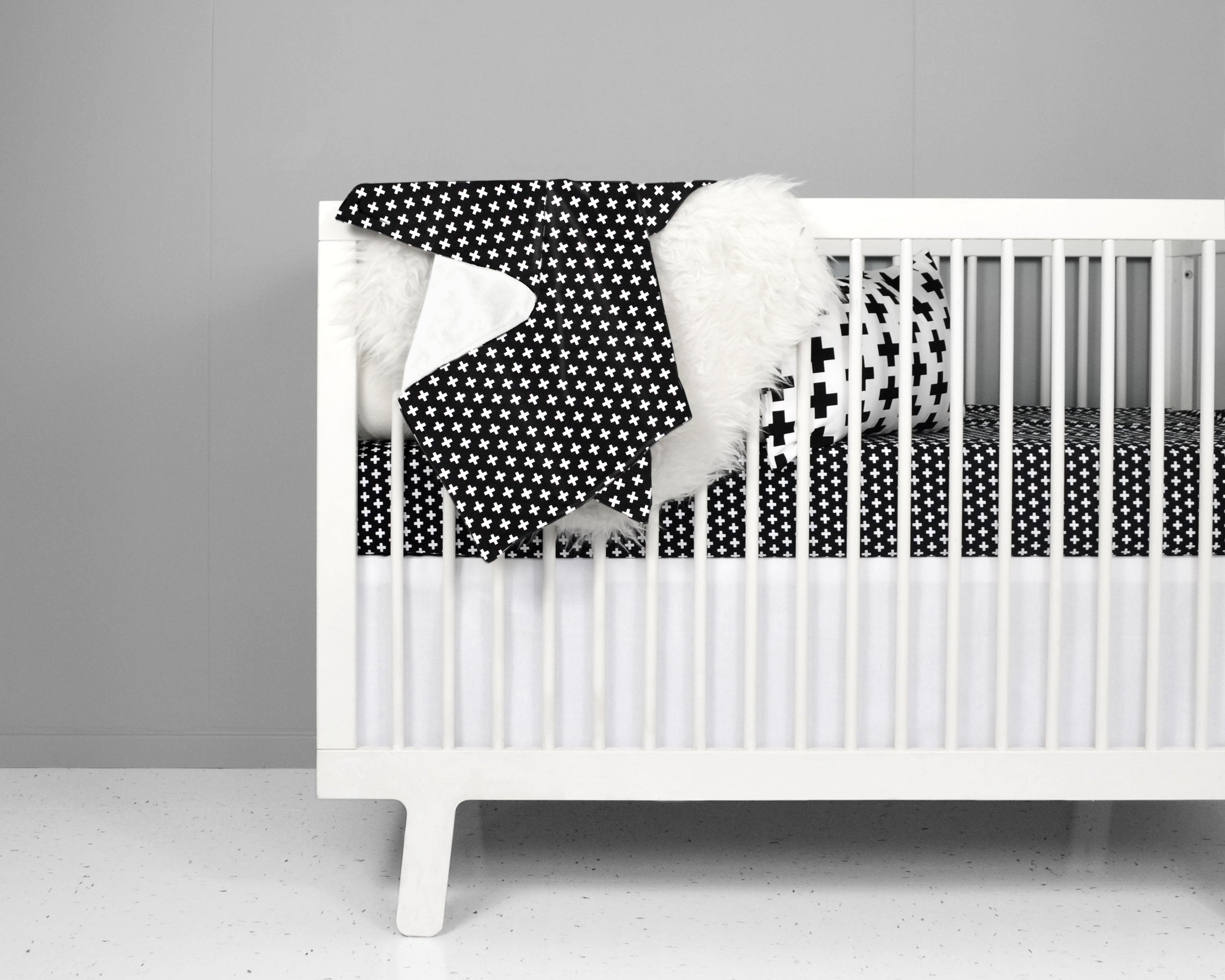 Lina Classic Crib Bedding Set featuring black and white swiss cross design with a fitted sheet, black cross blanket, and crib skirt.