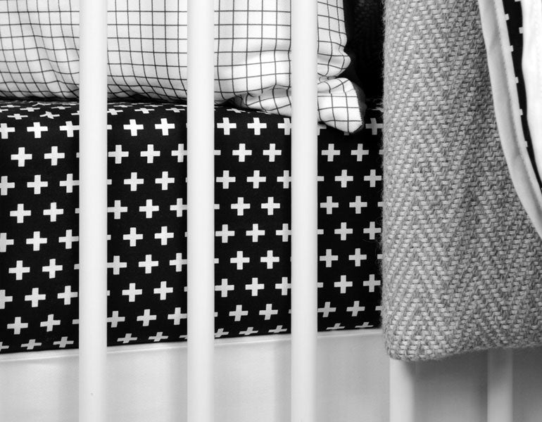 Lina Classic Crib Bedding Set featuring black and white swiss cross design with a fitted sheet, black cross blanket, and crib skirt.