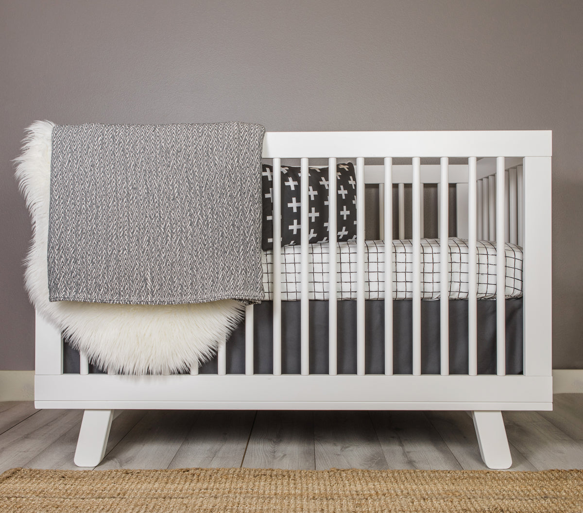 Luca Crib Bedding Set featuring a modern black and white grid pattern with a charcoal blanket and crib skirt, designed for stylish nurseries.