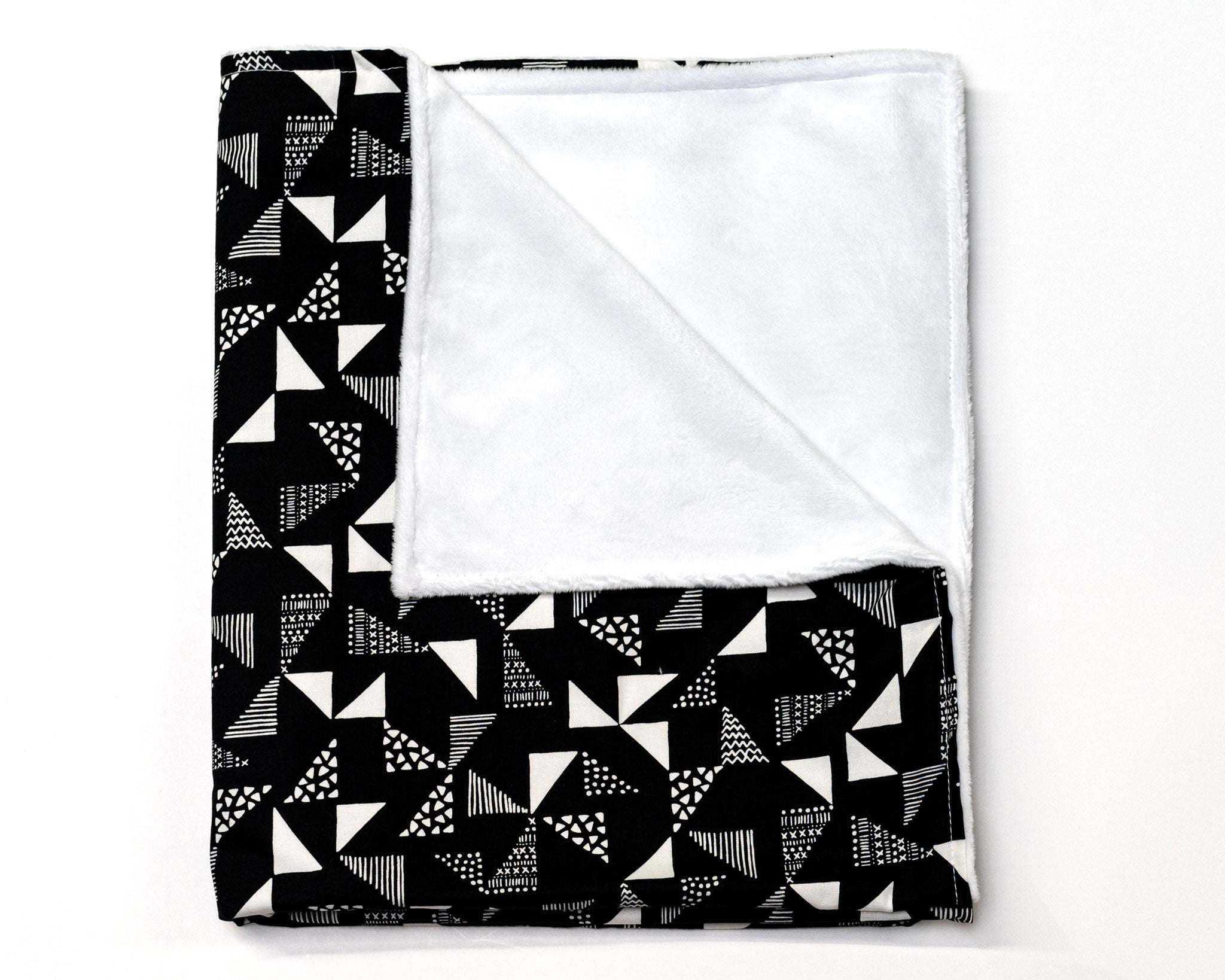 Pinwheels Deluxe Crib Bedding Set featuring gray and white triangles on a black backdrop, including crib skirt, fitted sheet, baby blanket, and lovey.
