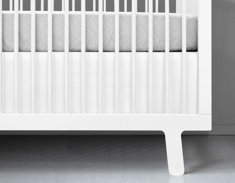 A crisp white crib skirt tailored for a standard crib, made from heavyweight cotton twill, enhancing nursery decor.