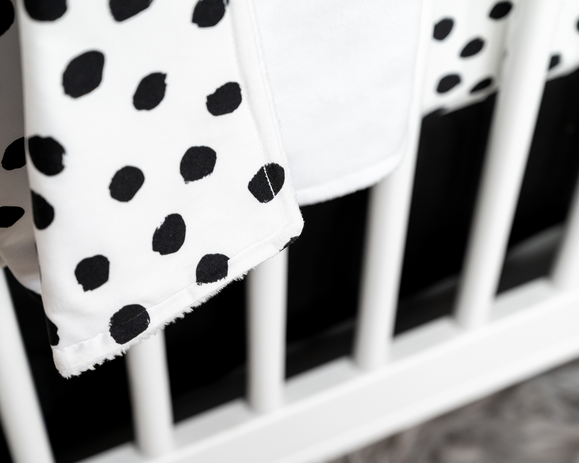 Zoe's Spots & Dots Baby Blanket featuring playful black dots on a white background, soft minky backing, and premium cotton fabric.