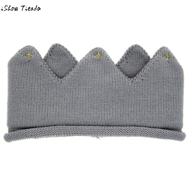 A cute baby wearing a knitted crown-shaped hat, showcasing a soft cotton material in a playful cartoon pattern, perfect for newborns and toddlers.
