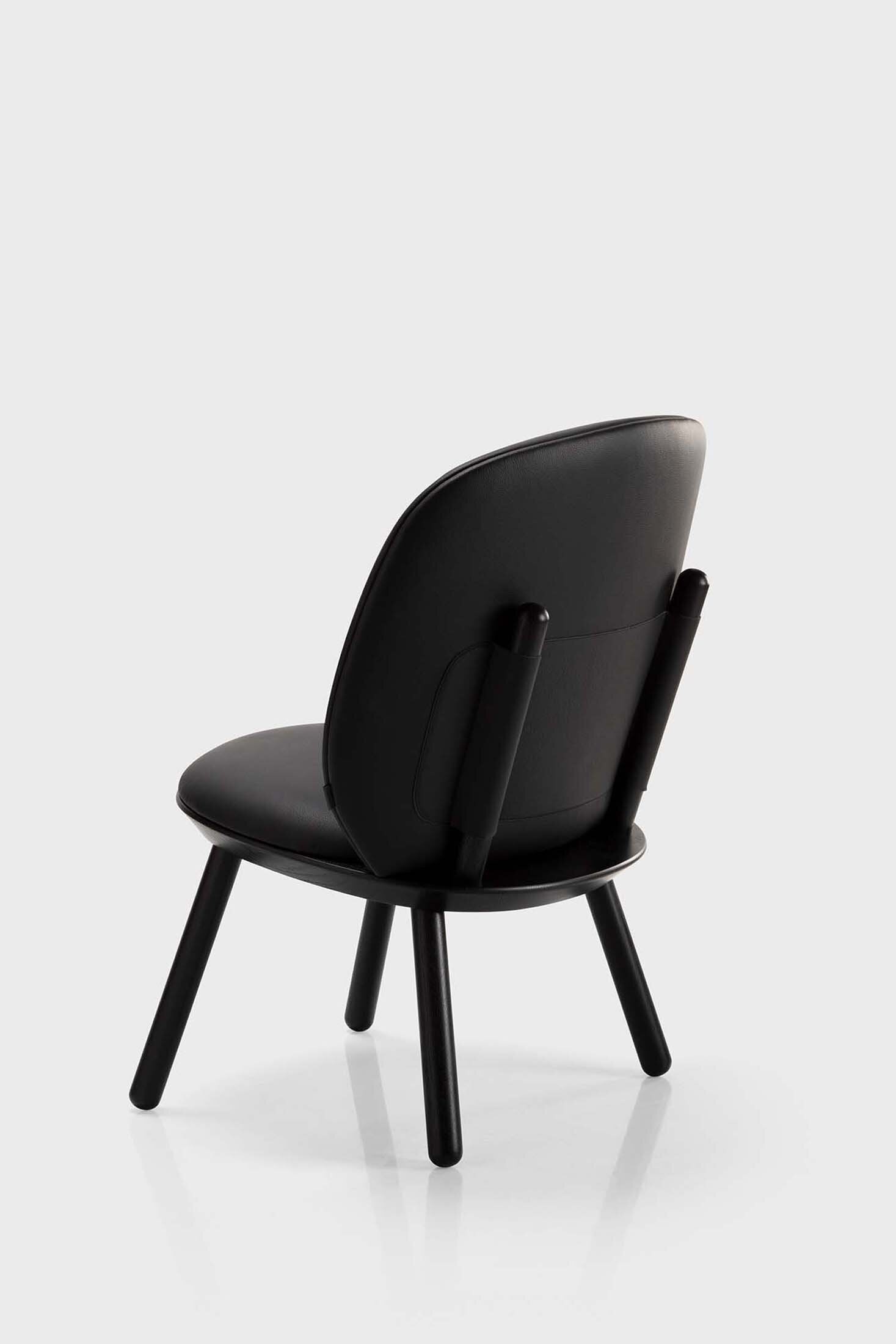 Naïve Low Chair featuring a large leather strap, wooden body, and textile upholstery, designed for comfort and style.