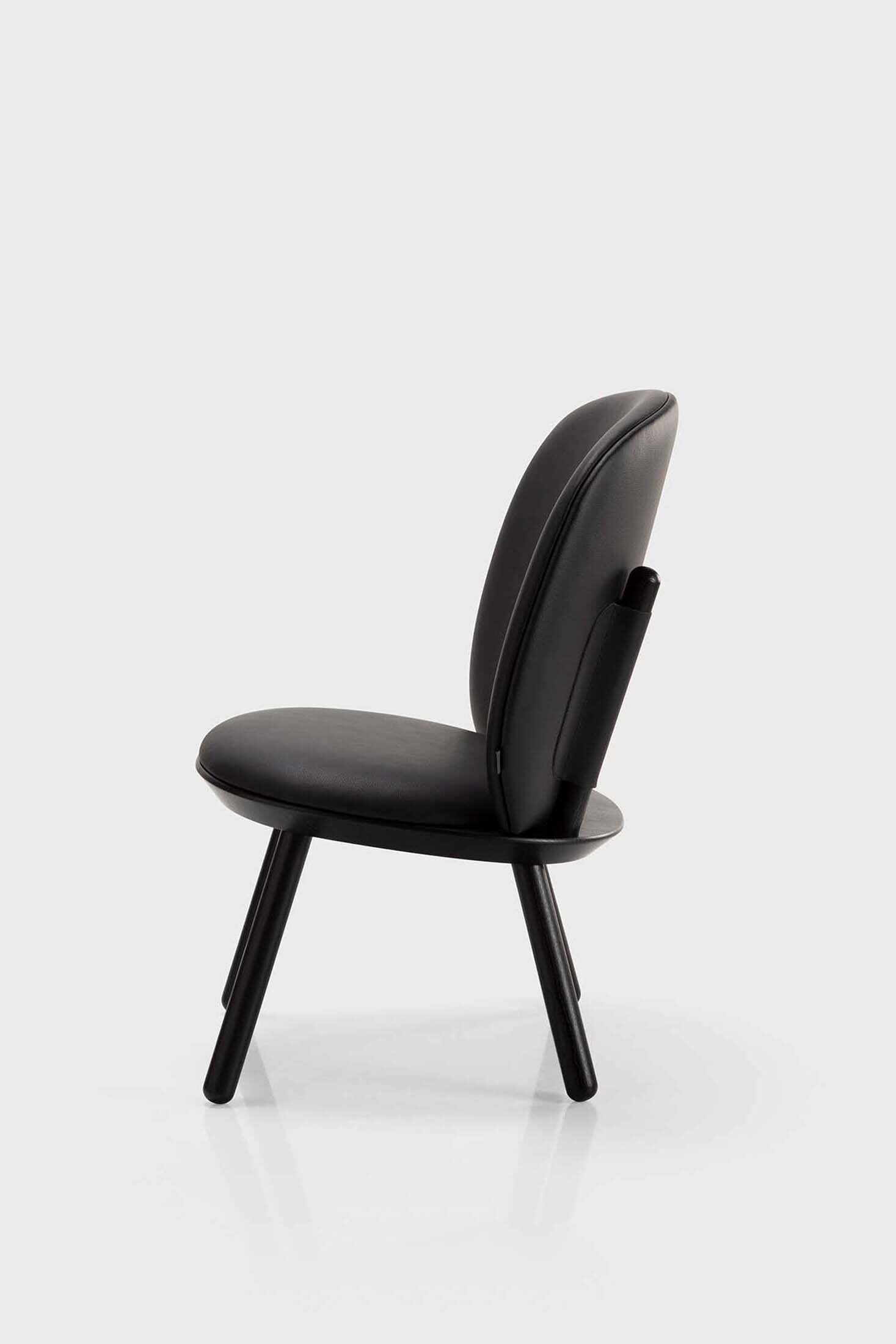 Naïve Low Chair featuring a large leather strap, wooden body, and textile upholstery, designed for comfort and style.