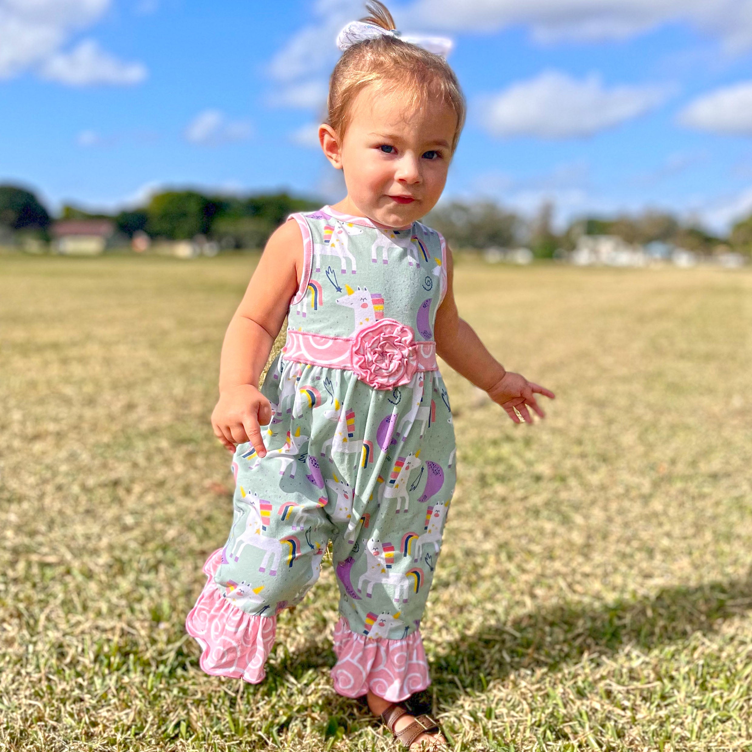 AnnLoren Boutique Baby Girls Unicorn & Rainbow Romper featuring original unicorn print, pink swirl ruffles, and snap closures.