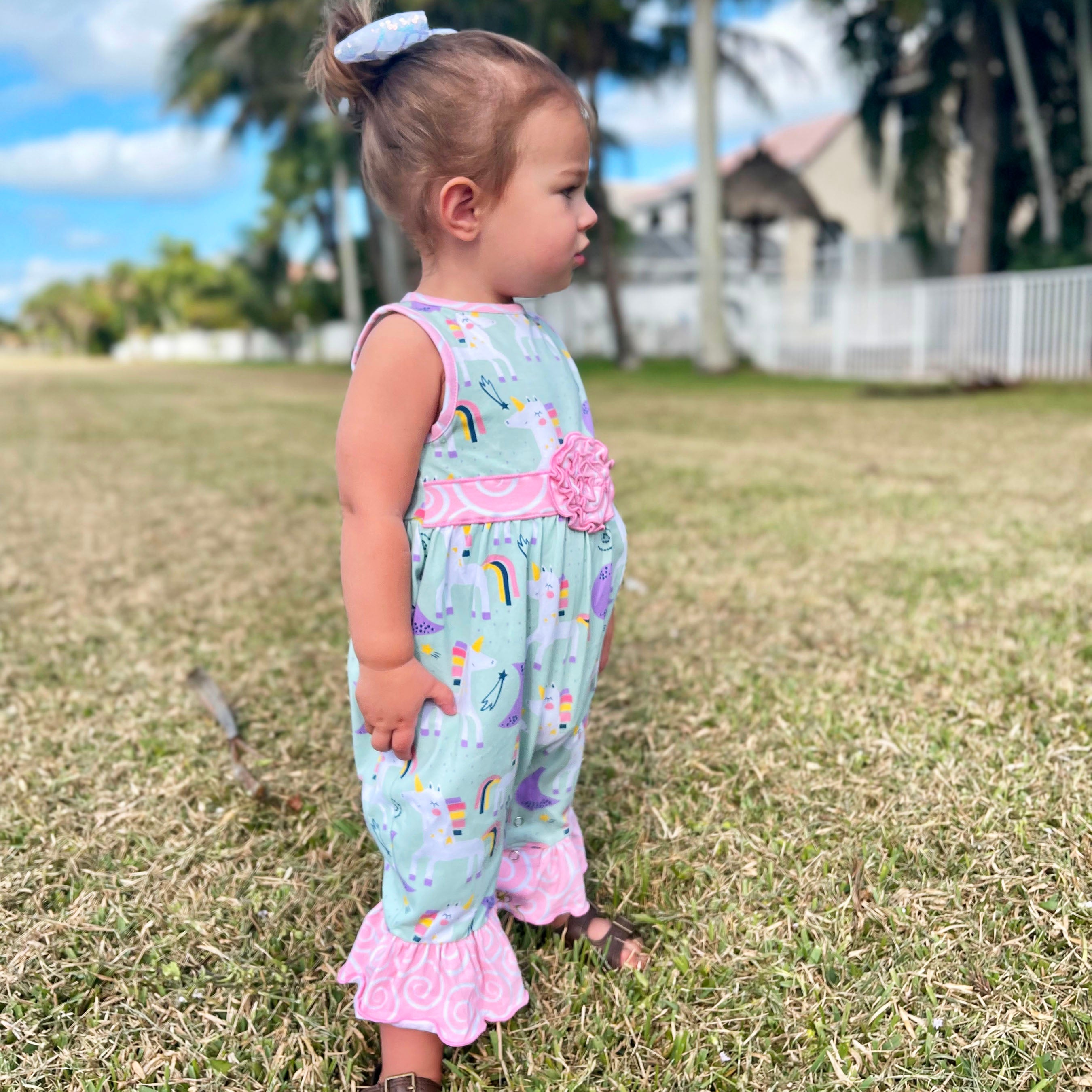 AnnLoren Boutique Baby Girls Unicorn & Rainbow Romper featuring original unicorn print, pink swirl ruffles, and snap closures.