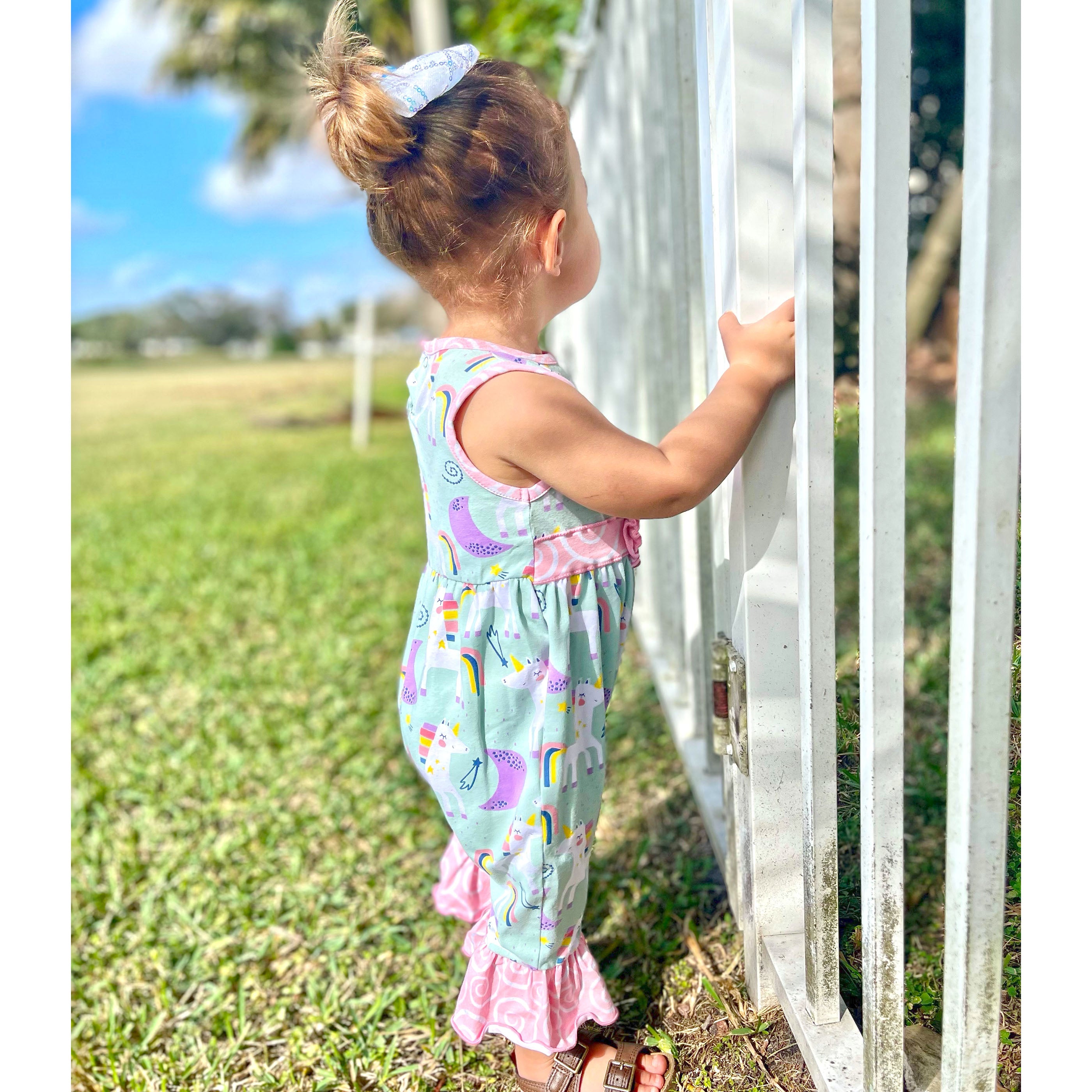 AnnLoren Boutique Baby Girls Unicorn & Rainbow Romper featuring original unicorn print, pink swirl ruffles, and snap closures.