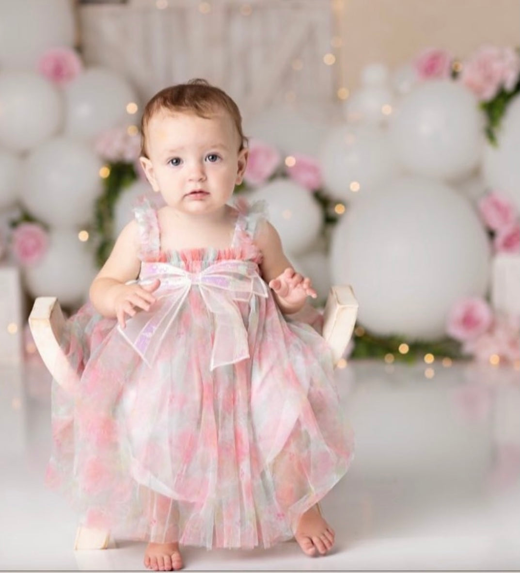 A charming pink floral tulle dress featuring a big sequined bow at the front, perfect for summer parties.
