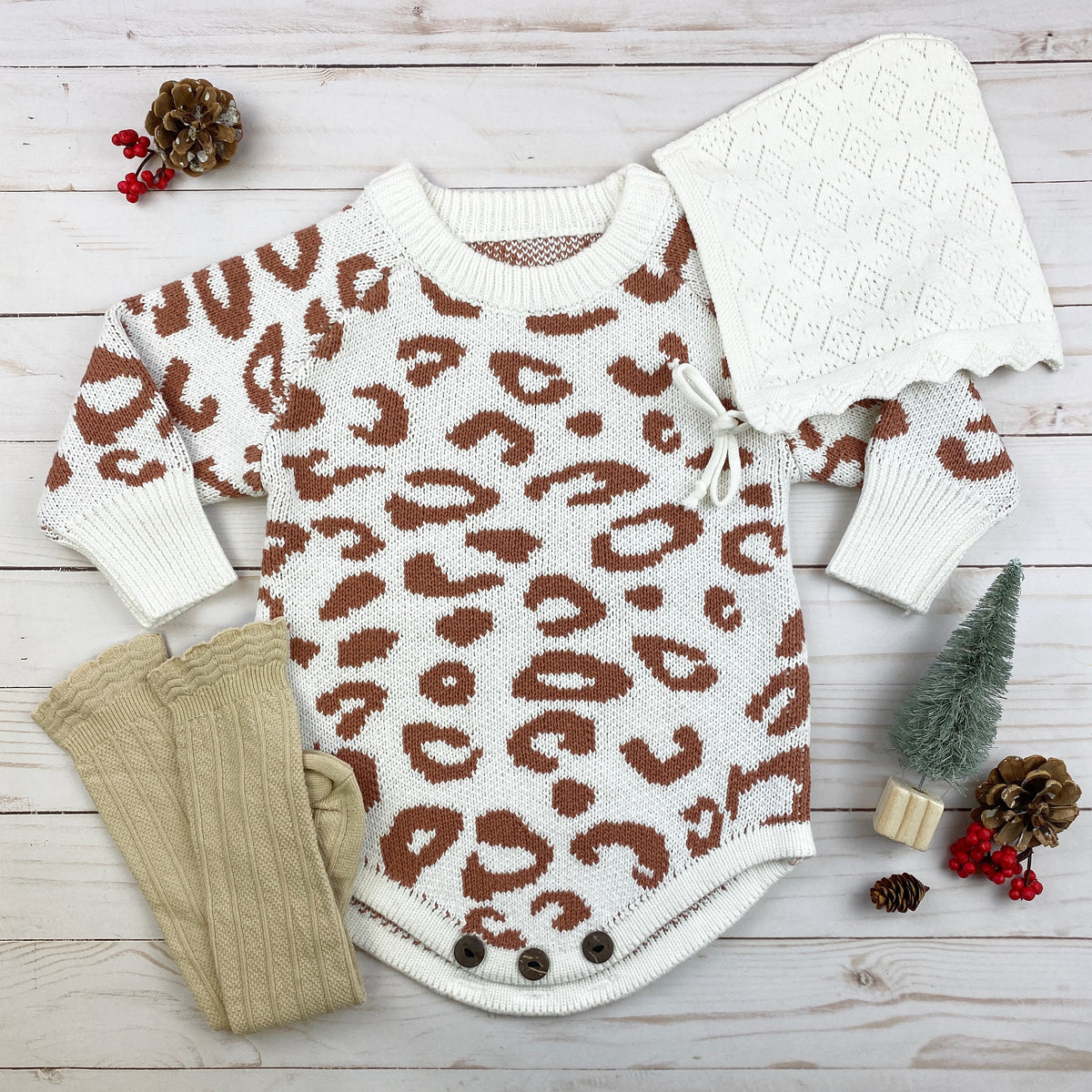 Cozy leopard print knitted onesie in white and pink with brown spots, featuring wooden button closure for easy diaper changes.