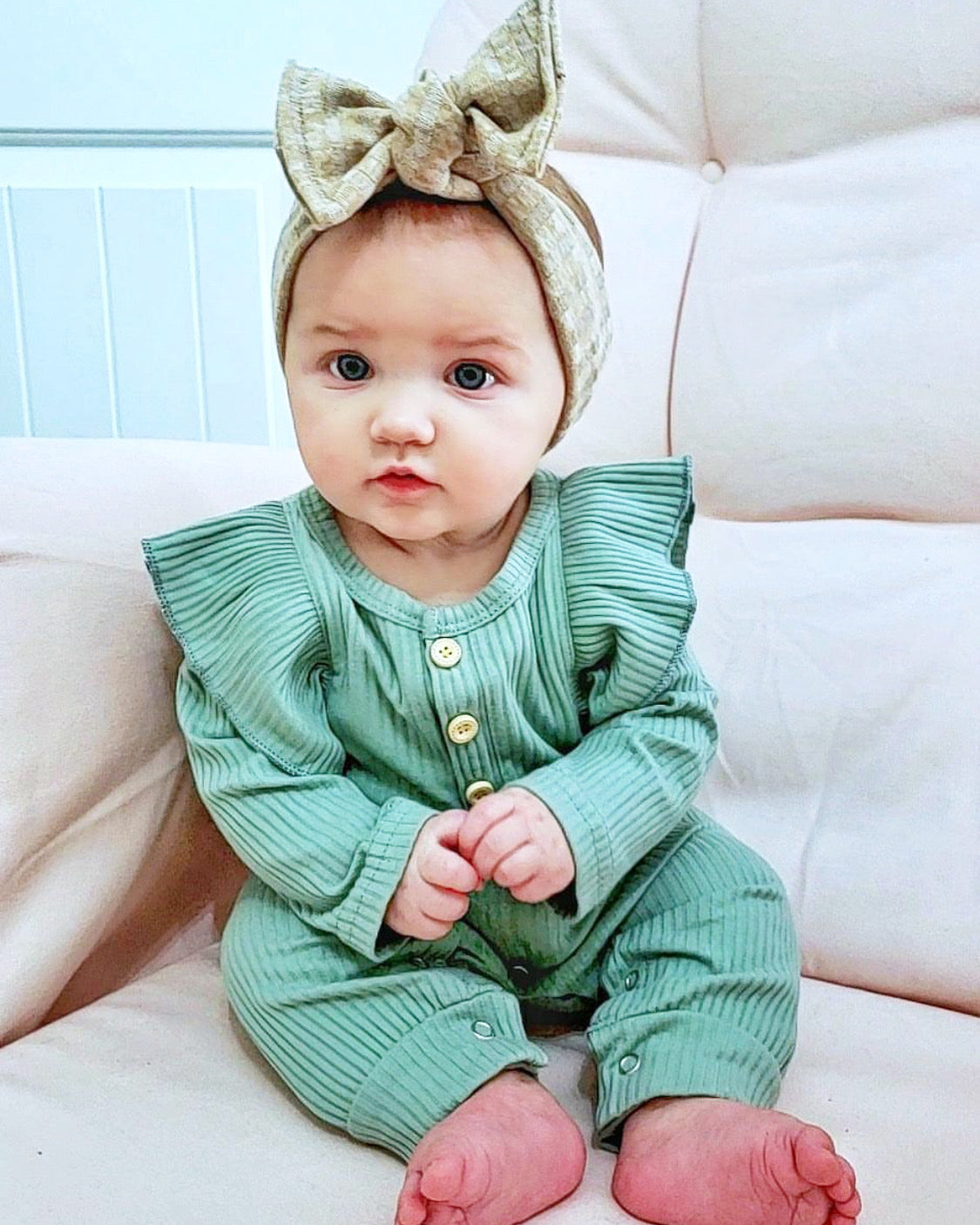 A colorful long sleeve ruffle romper for babies, featuring soft ribbed cotton fabric, ruffles along the seams, and wooden button details.