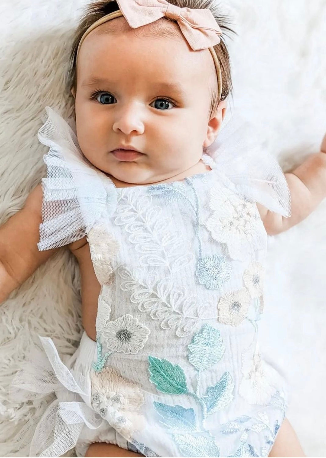 Louella embroidered romper featuring white floral design with tulle ruffles and snap closure.