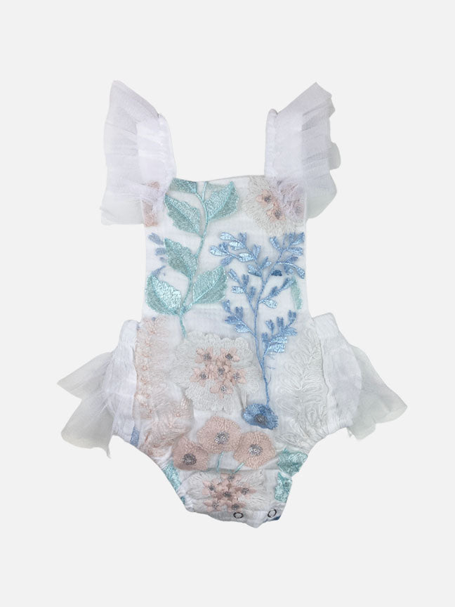 Louella embroidered romper featuring white floral design with tulle ruffles and snap closure.