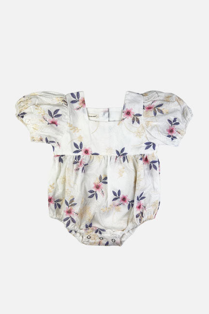 Maeve embroidered onesie featuring a white floral base with pink flowers and cream embroidery, designed with puff sleeves and snap crotch closure.