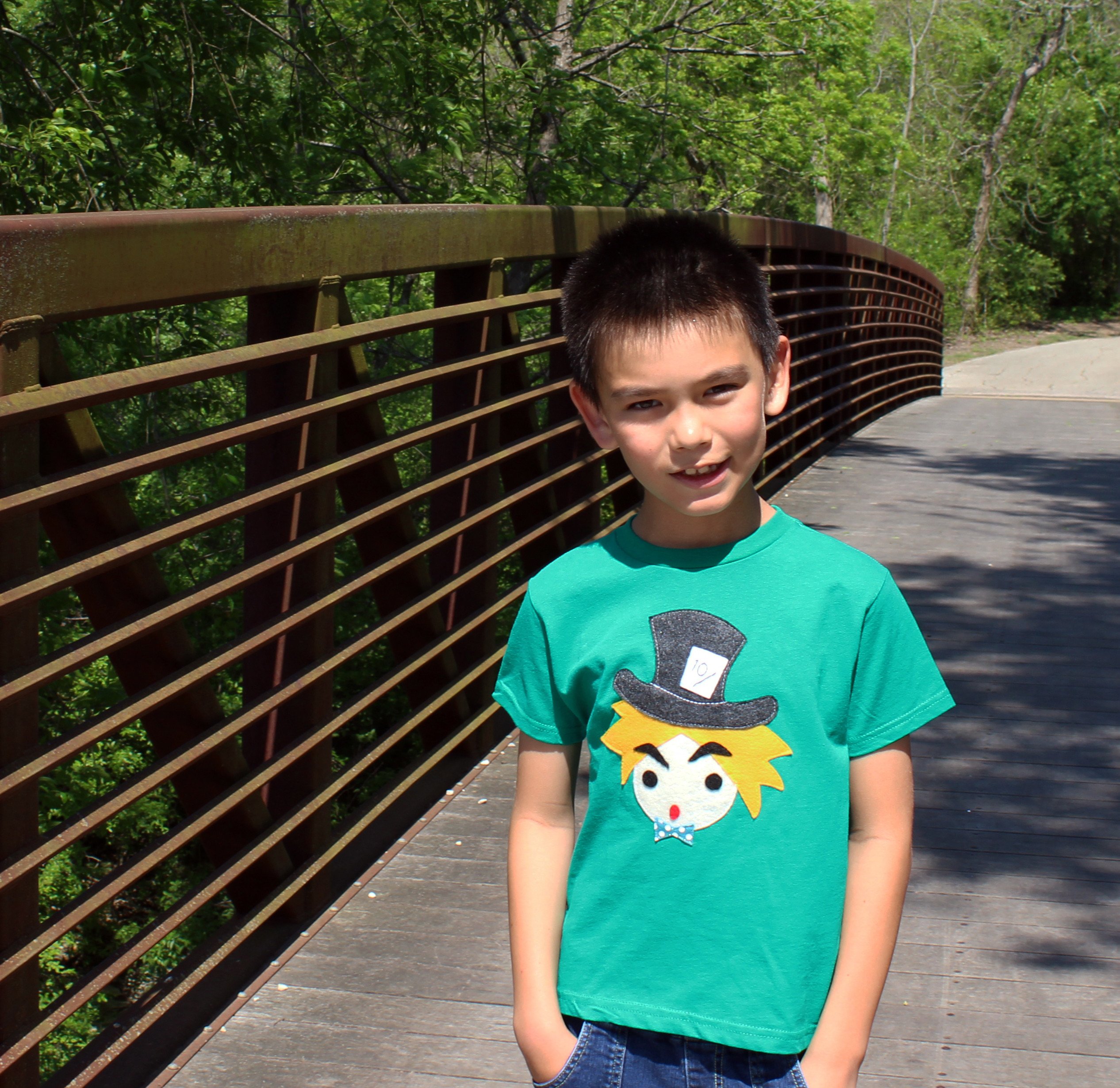 A colorful handmade kids t-shirt featuring The Hatter from Alice's Adventure in Wonderland, with eco felt appliqué design.