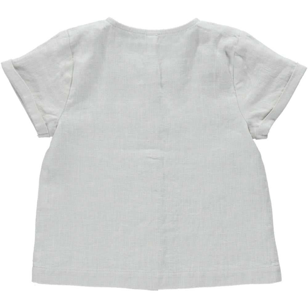 Top Petunia Creme featuring short sleeves, rolled cuffs, and olive wood buttons, made from soft natural linen fabric.