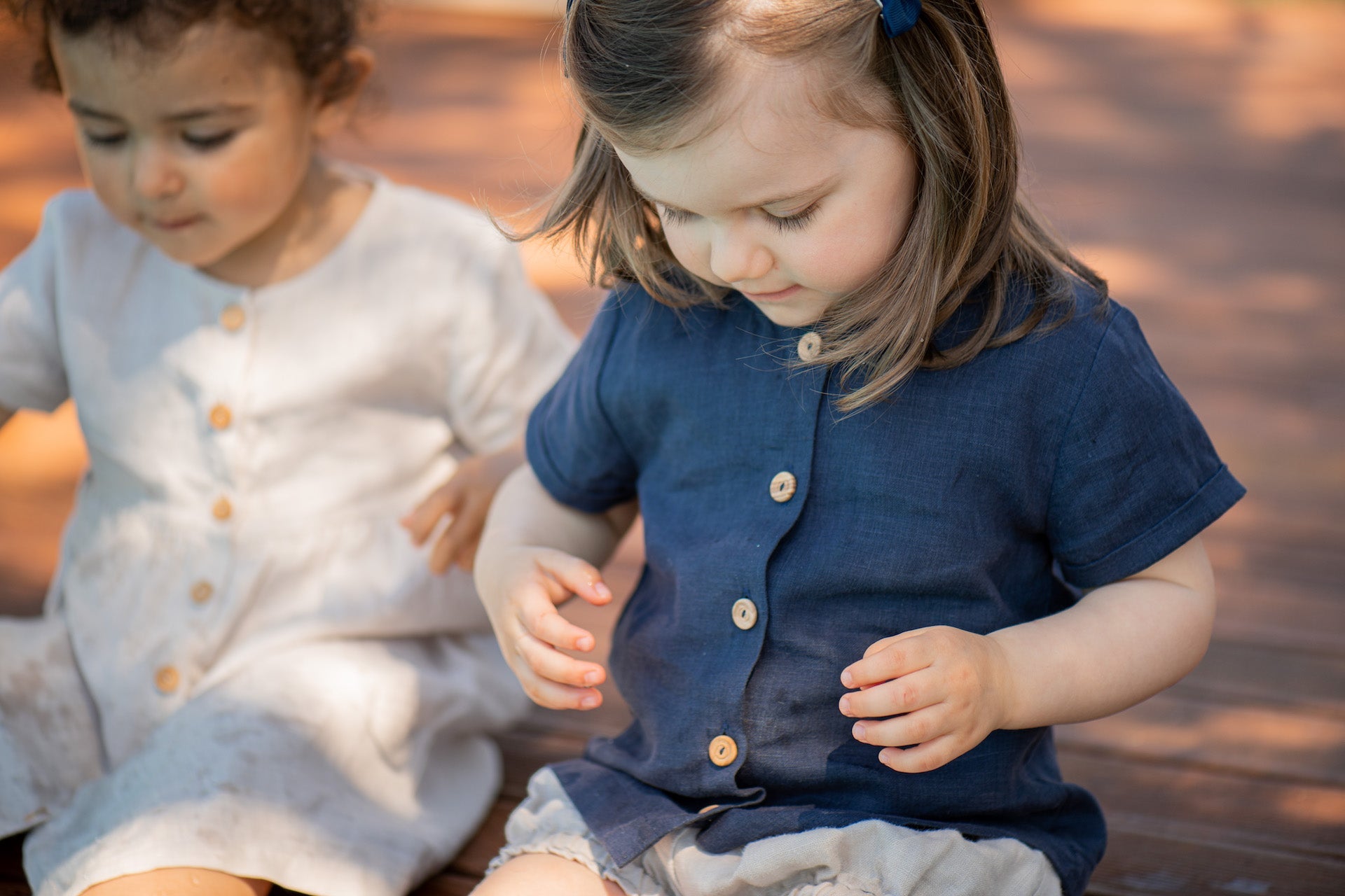 Top Petunia Creme featuring short sleeves, rolled cuffs, and olive wood buttons, made from soft natural linen fabric.