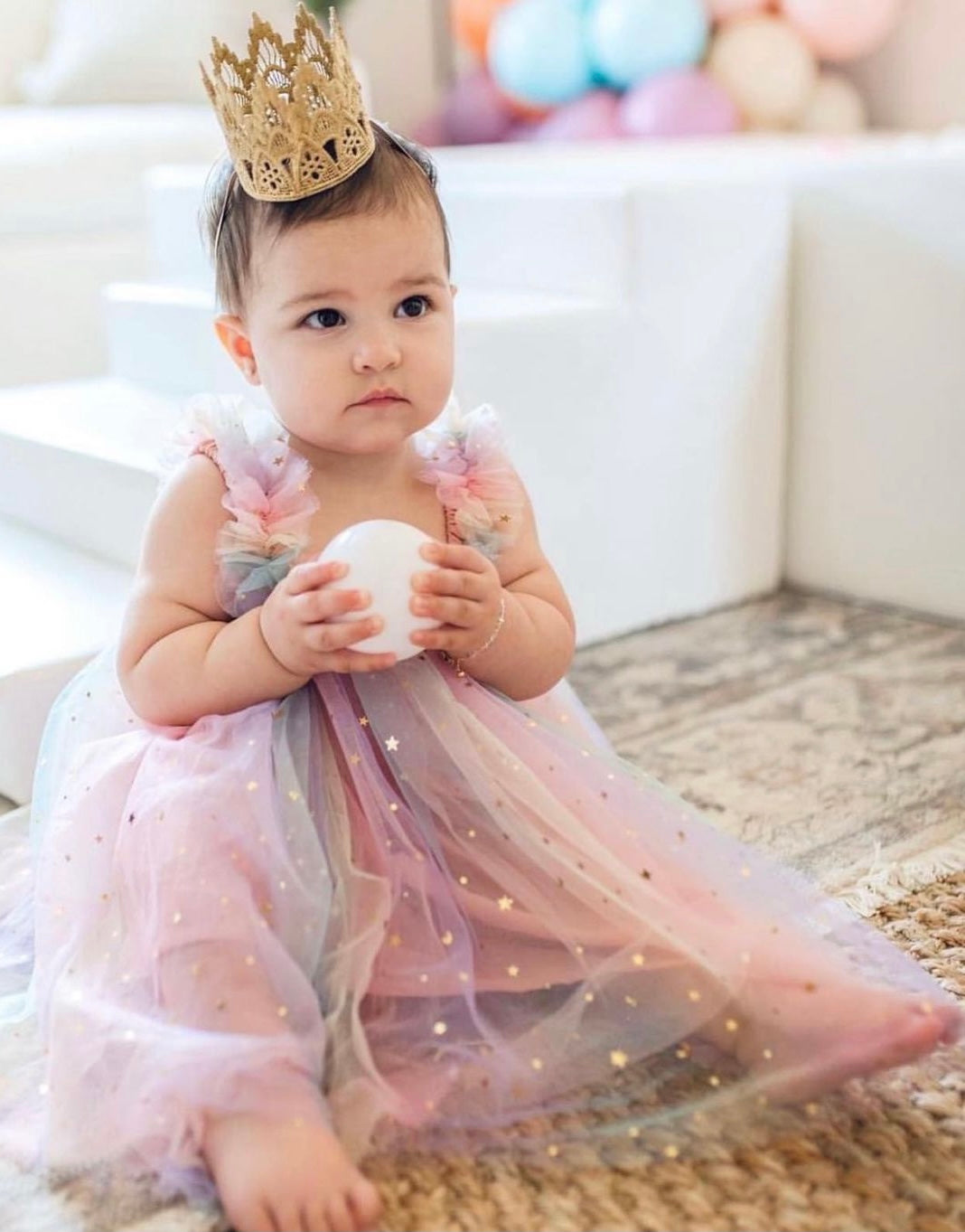 A beautiful tulle dress featuring a moon and stars print with a gradient of pastel colors including pink, purple, teal, and yellow.