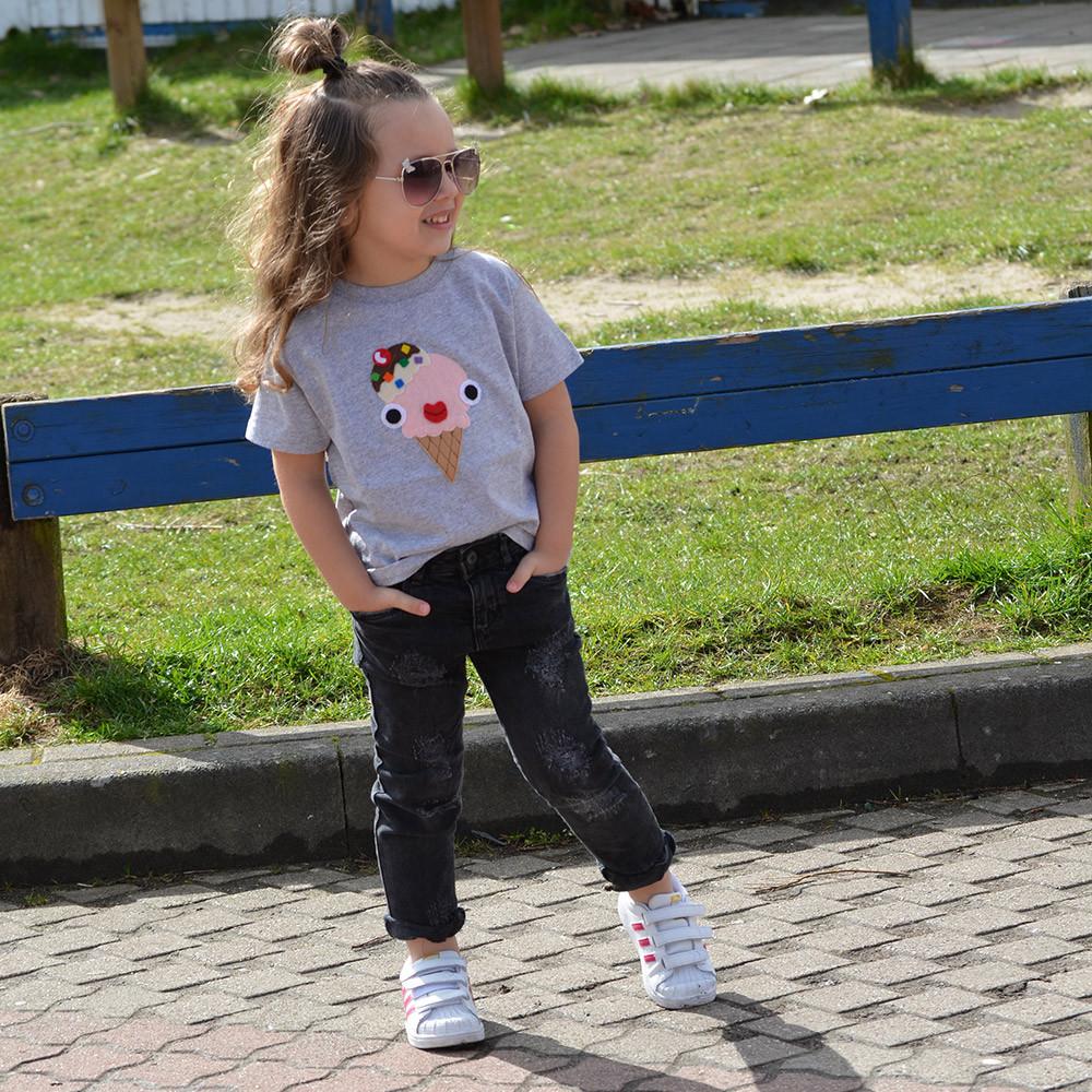 A colorful kid's shirt featuring a chocolate ice-cream design with green topping and a cherry on top, handmade with appliquéd felt pieces.