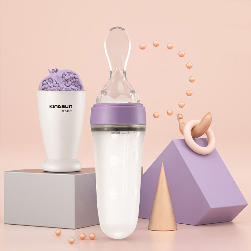 A purple silicone baby feeding bottle with a squeeze spoon, designed for easy feeding of cereals and semi-liquid foods.