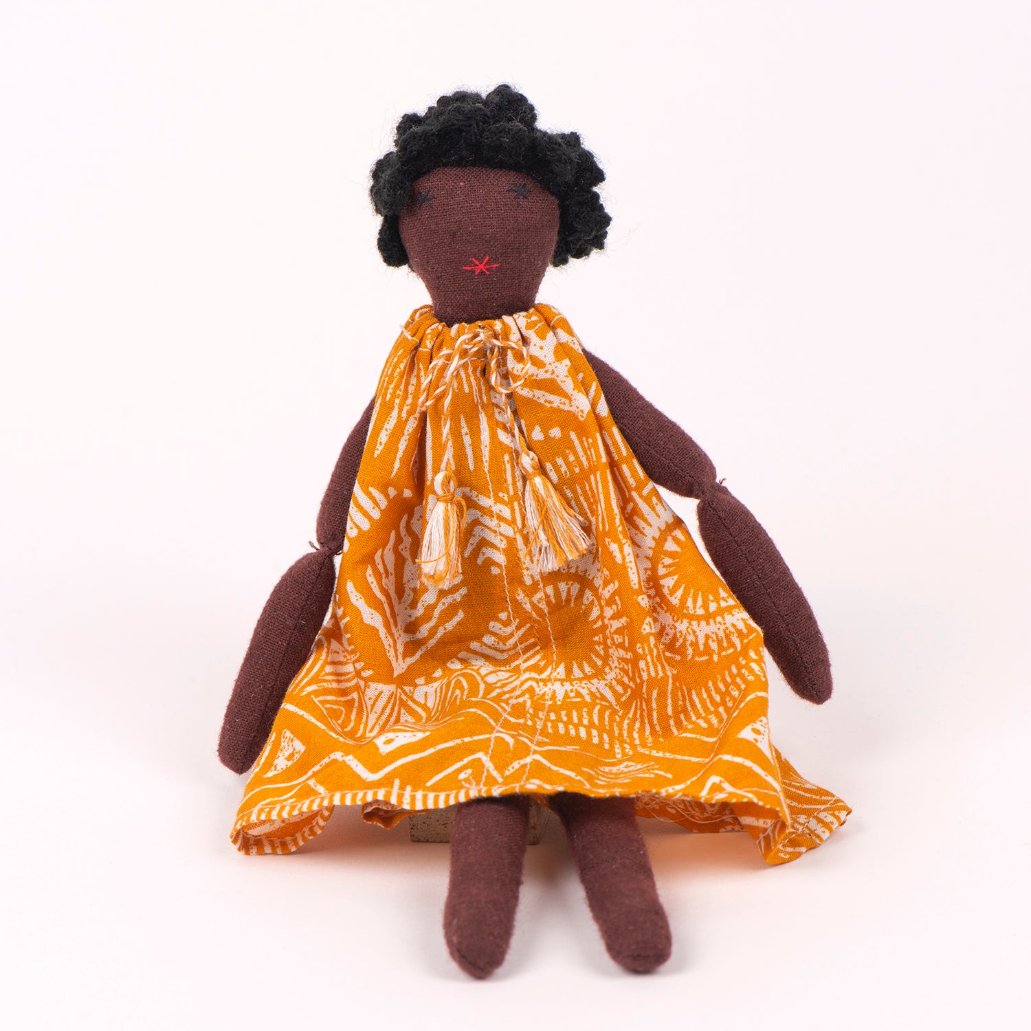 Soumba Mini doll dressed in vibrant print, symbolizing hope and sustainability, with bedding in a foldable box.