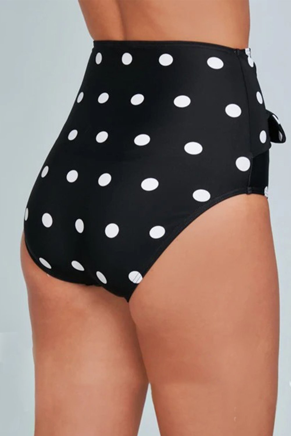 Women's black swim bottoms with polka dot print and front tie detail, designed for high waist fit and full coverage.