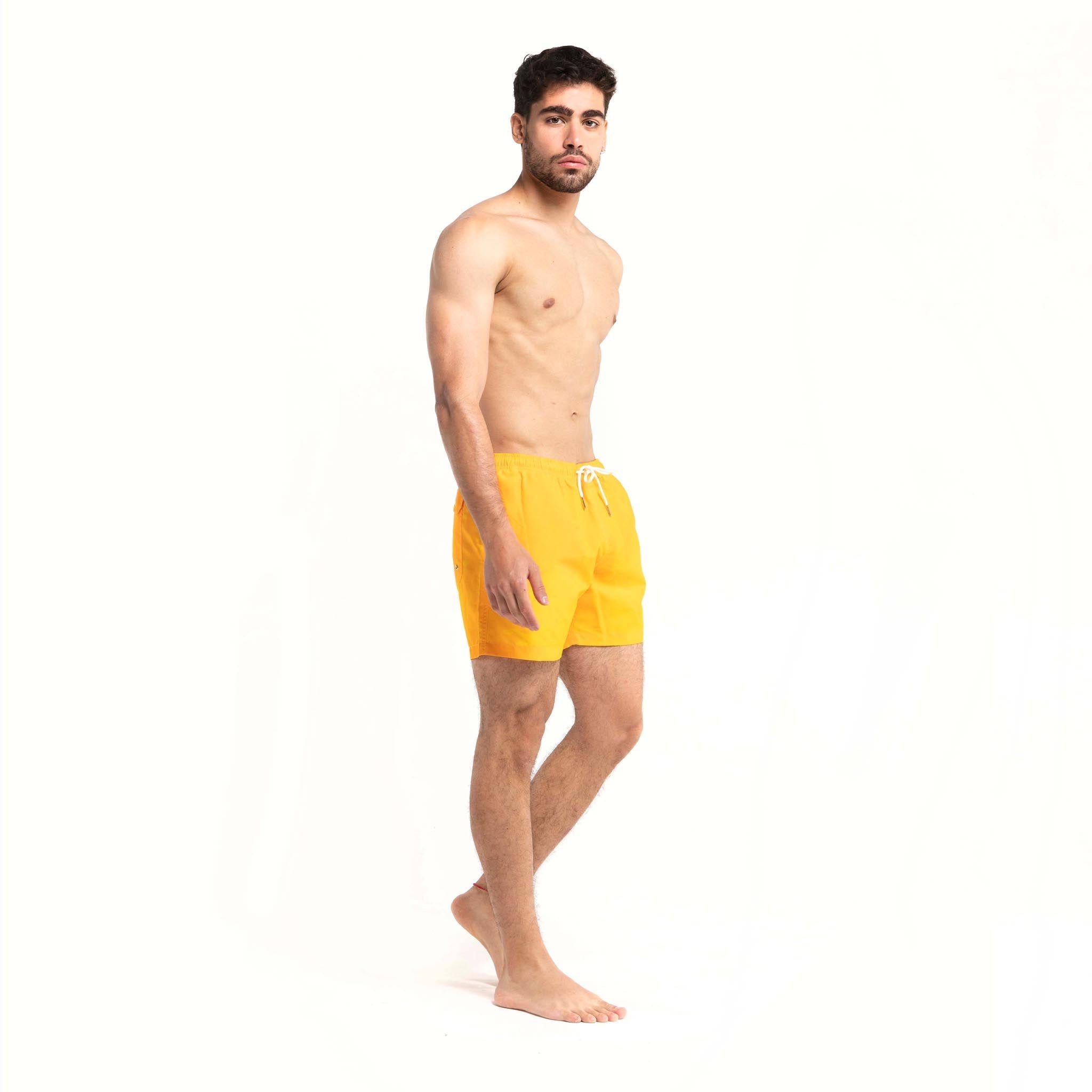 Color-changing swim trunks transitioning from yellow to orange in water, showcasing eco-friendly fabric and stylish design.