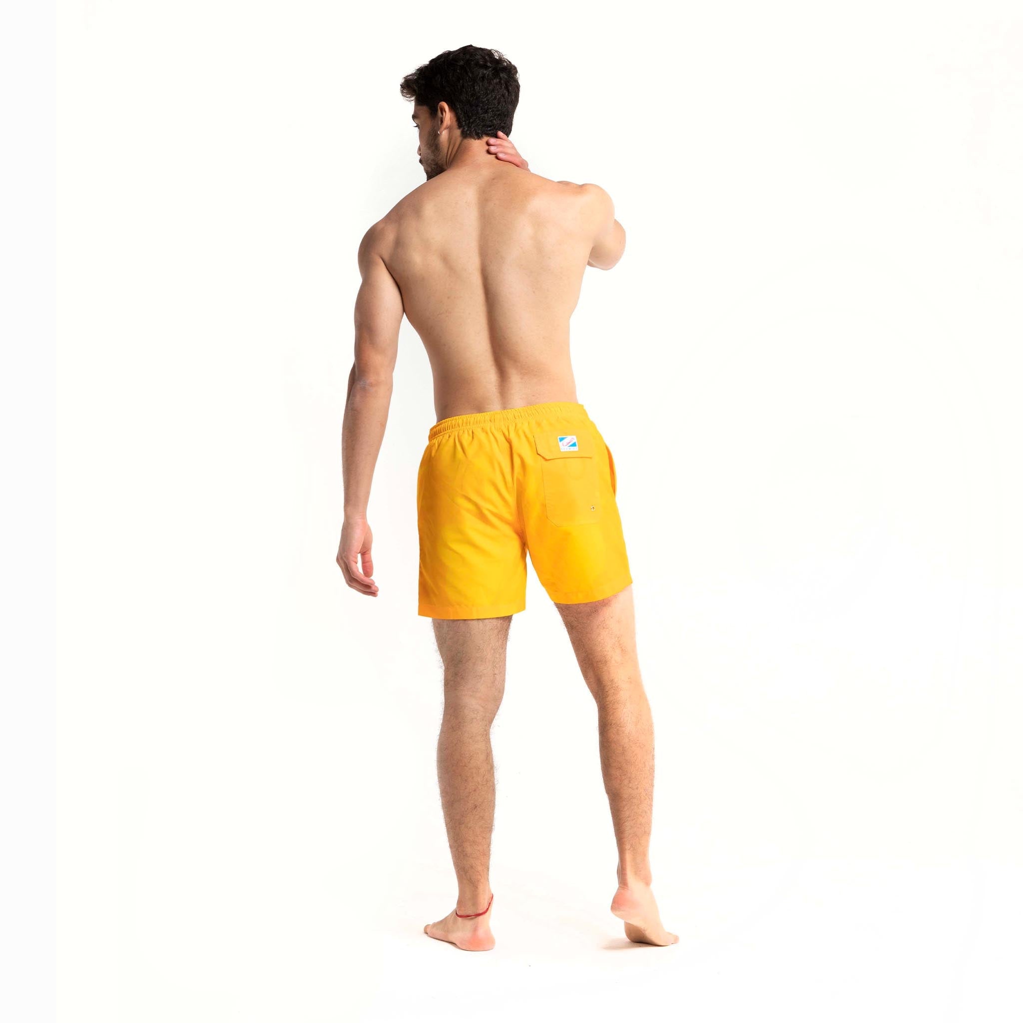 Color-changing swim trunks transitioning from yellow to orange in water, showcasing eco-friendly fabric and stylish design.