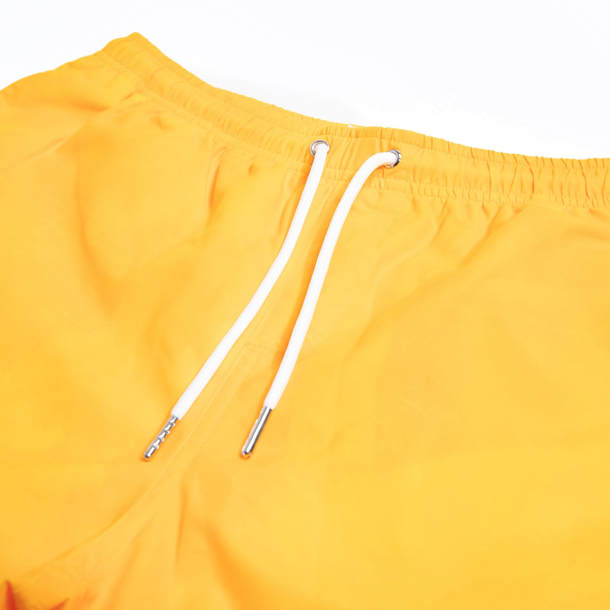 Color-changing swim trunks transitioning from yellow to orange in water, showcasing eco-friendly fabric and stylish design.