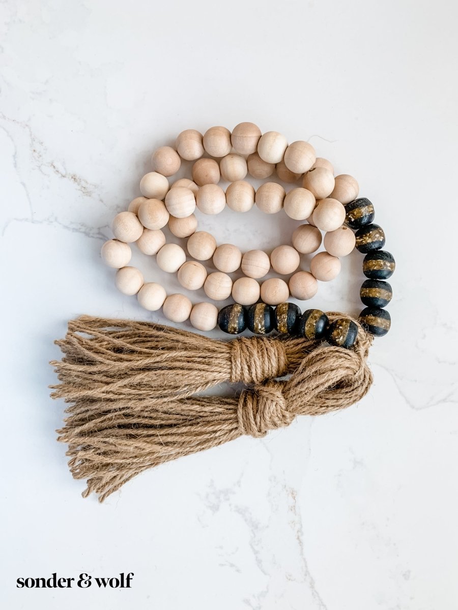 A beautifully crafted 4ft wood bead garland featuring 10 Black Kente Krobo beads and jute tassels, perfect for home decor.