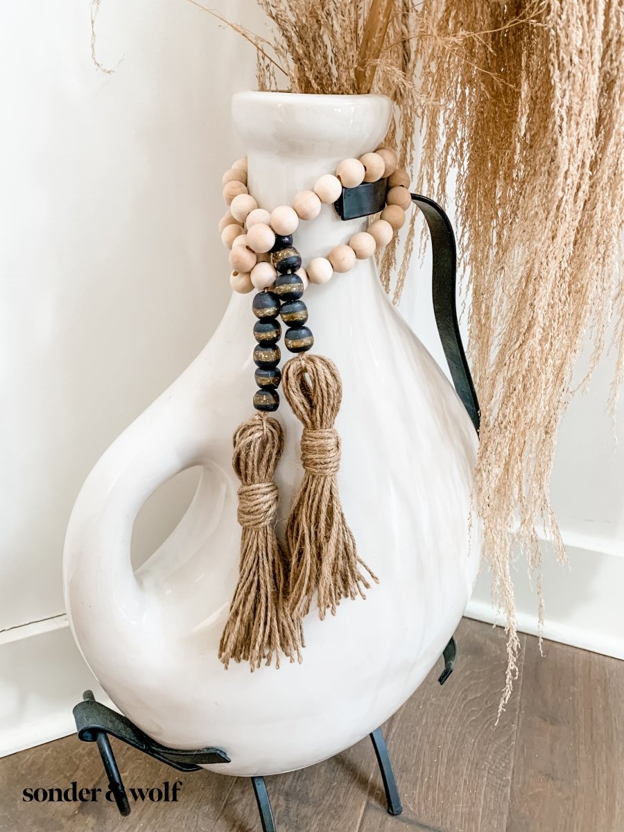 A beautifully crafted 4ft wood bead garland featuring 10 Black Kente Krobo beads and jute tassels, perfect for home decor.