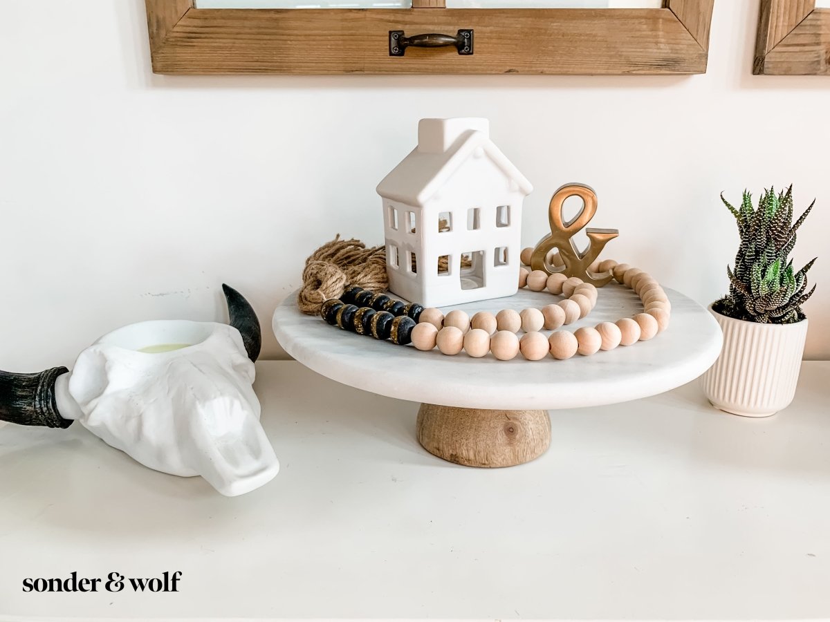 A beautifully crafted 4ft wood bead garland featuring 10 Black Kente Krobo beads and jute tassels, perfect for home decor.