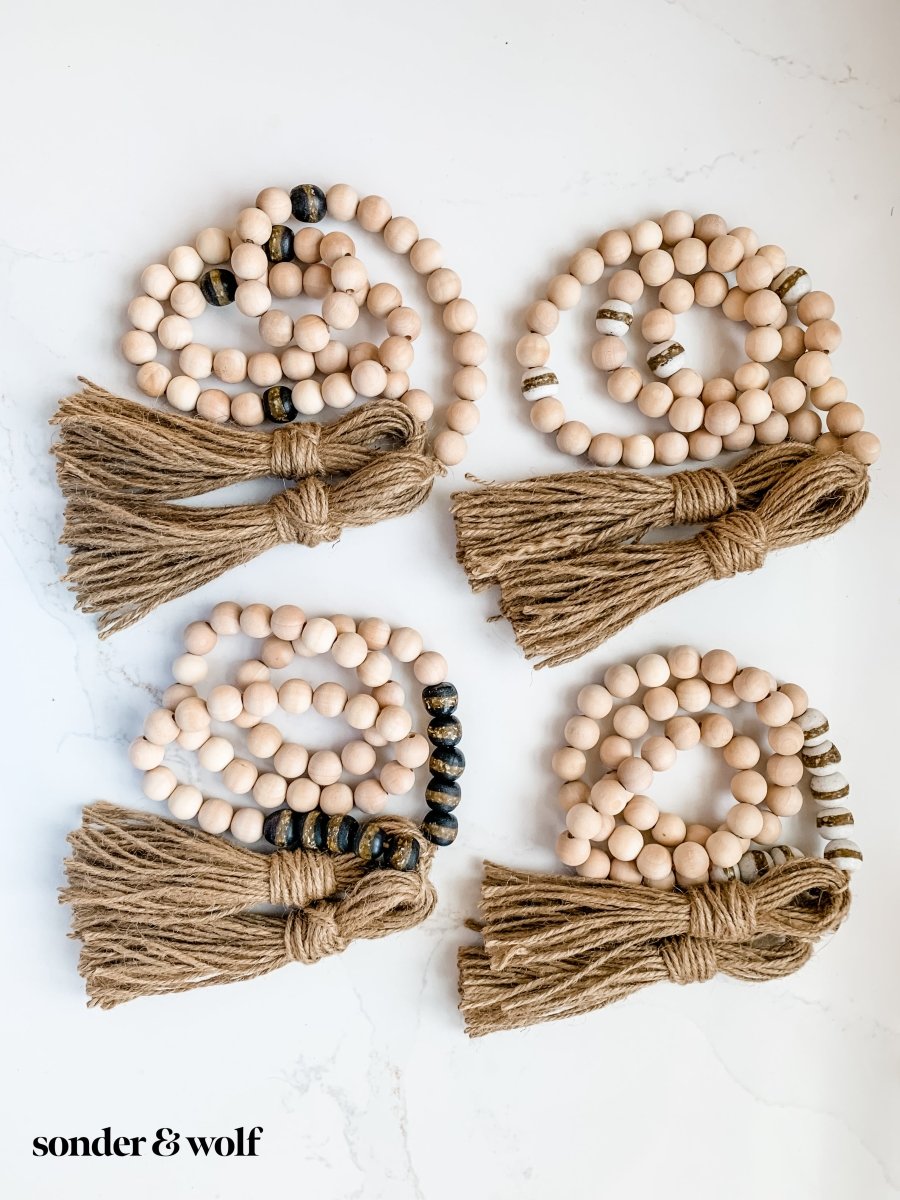 A beautifully crafted 4ft wood bead garland featuring 10 Black Kente Krobo beads and jute tassels, perfect for home decor.