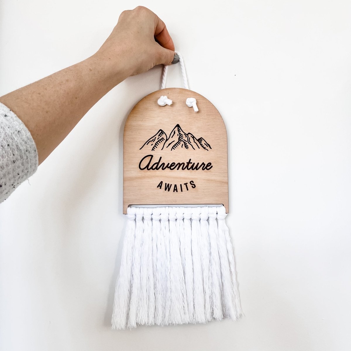 Adventure Awaits Half Moon Macrame Sign featuring laser cut lettering and macrame rope, perfect for home decor.