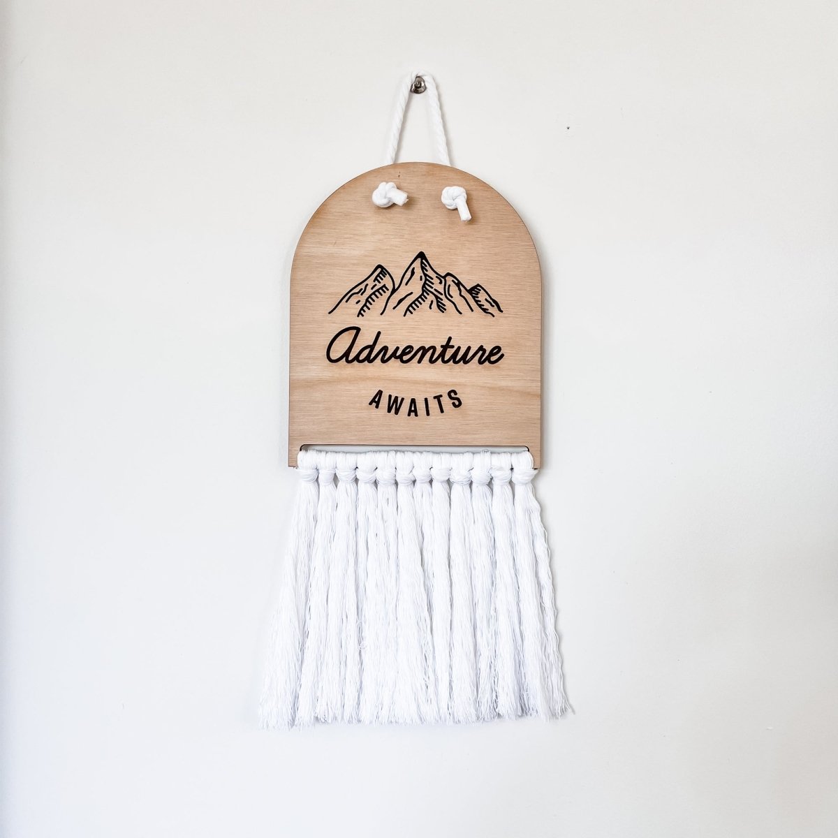 Adventure Awaits Half Moon Macrame Sign featuring laser cut lettering and macrame rope, perfect for home decor.