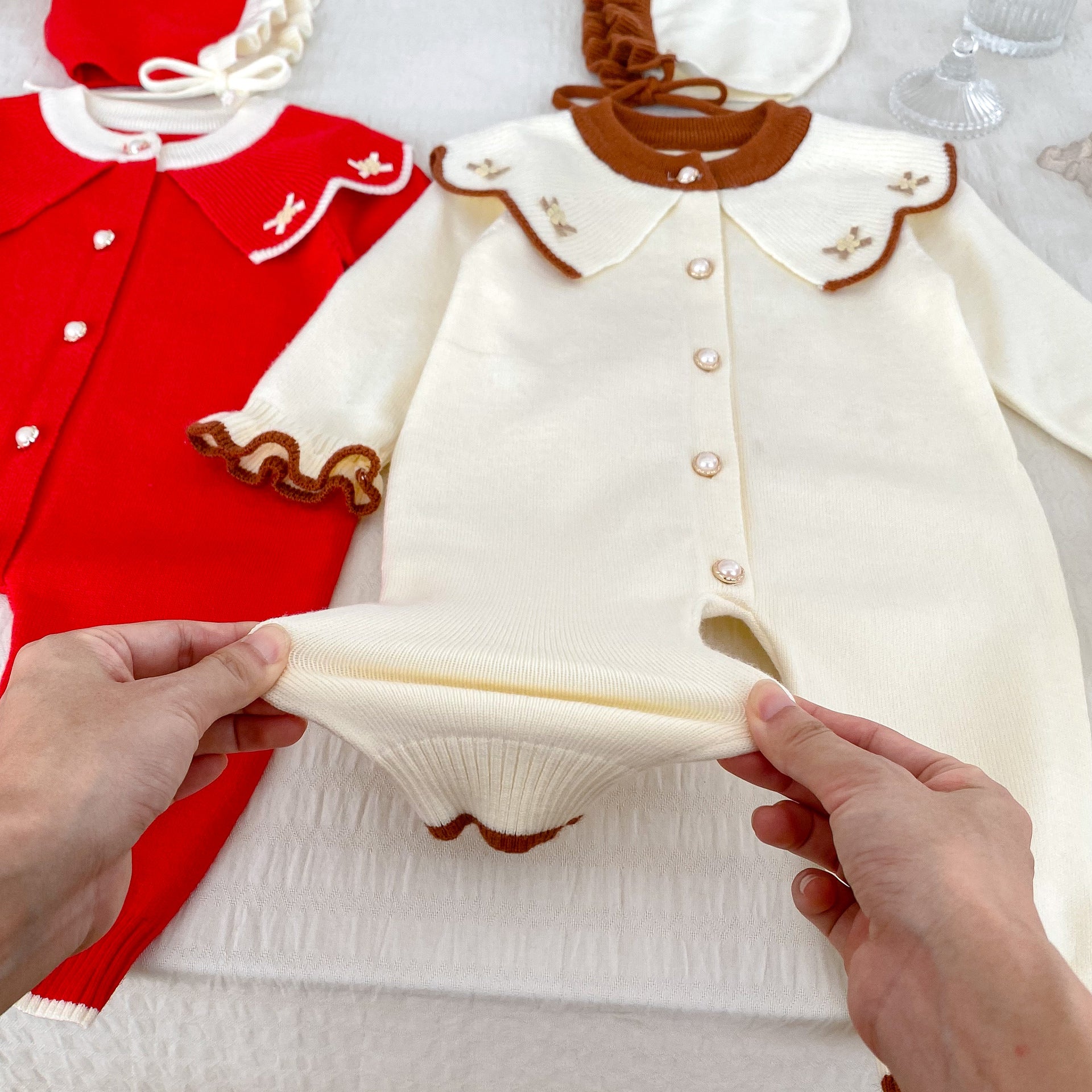 A cozy knitted top for baby girls featuring long sleeves, a floral pattern collar, available in red and apricot colors.