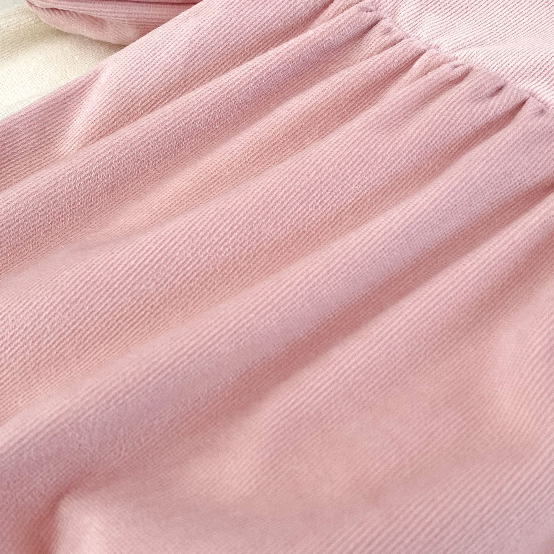 A cute baby girl wearing a long sleeves romper with a rabbits design in pink color, perfect for autumn.