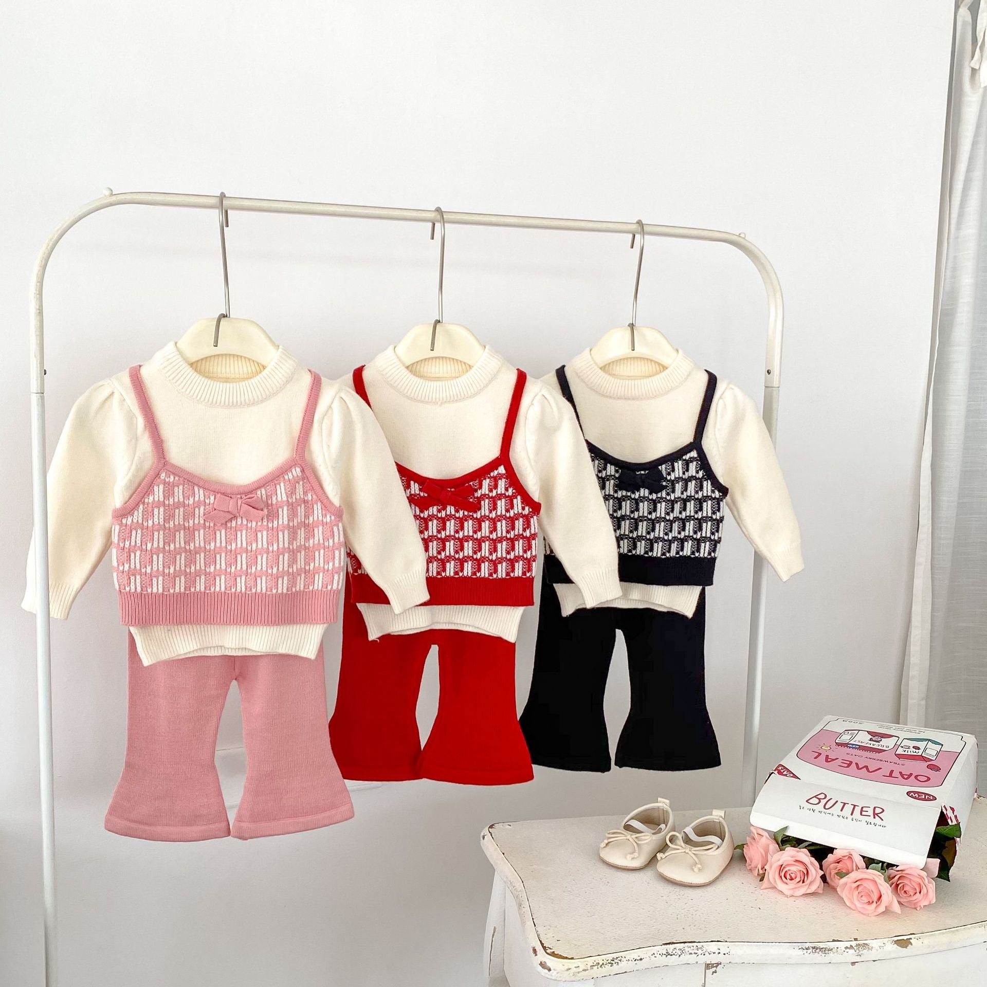 A stylish knitted top for baby girls featuring long sleeves and a colorful patchwork design in black, red, and pink.