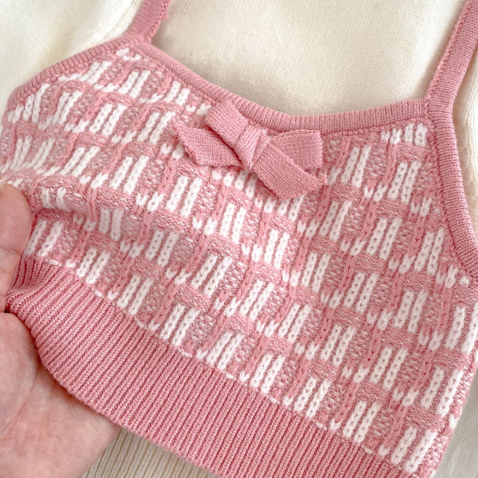 A stylish knitted top for baby girls featuring long sleeves and a colorful patchwork design in black, red, and pink.