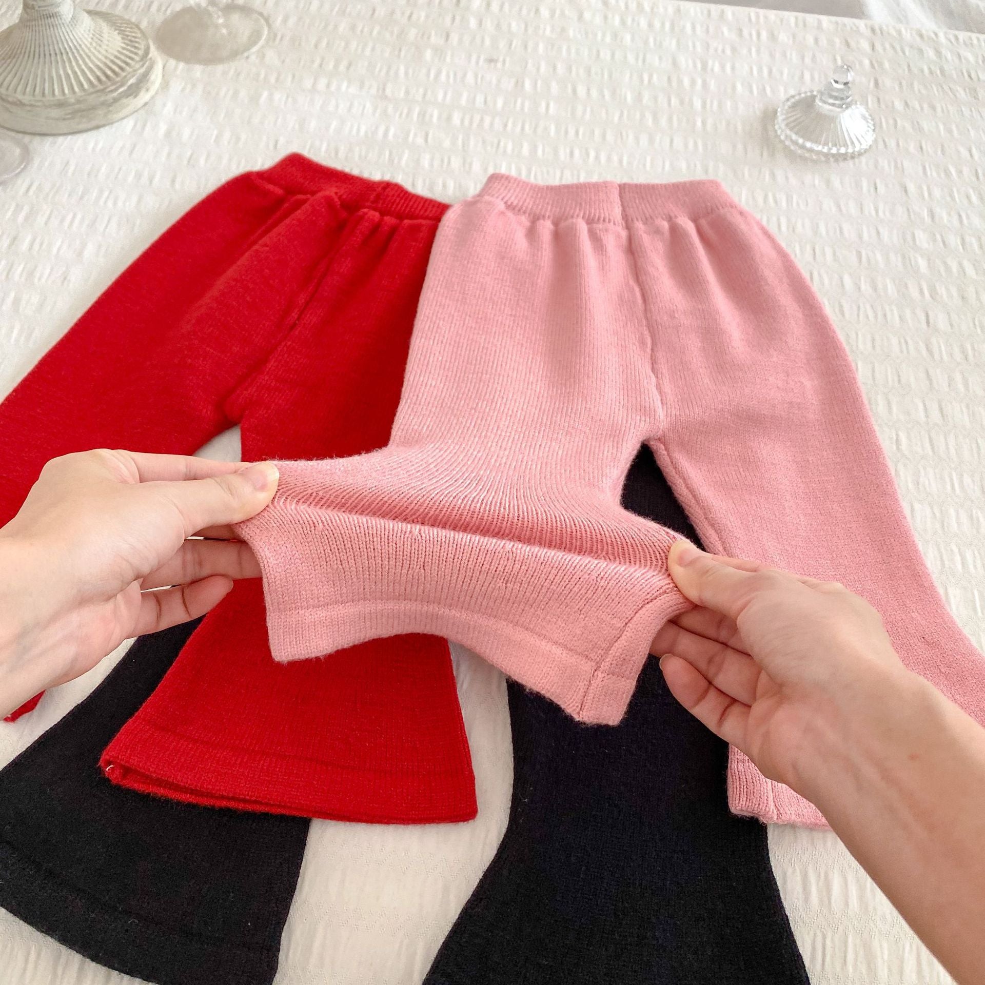 A stylish knitted top for baby girls featuring long sleeves and a colorful patchwork design in black, red, and pink.