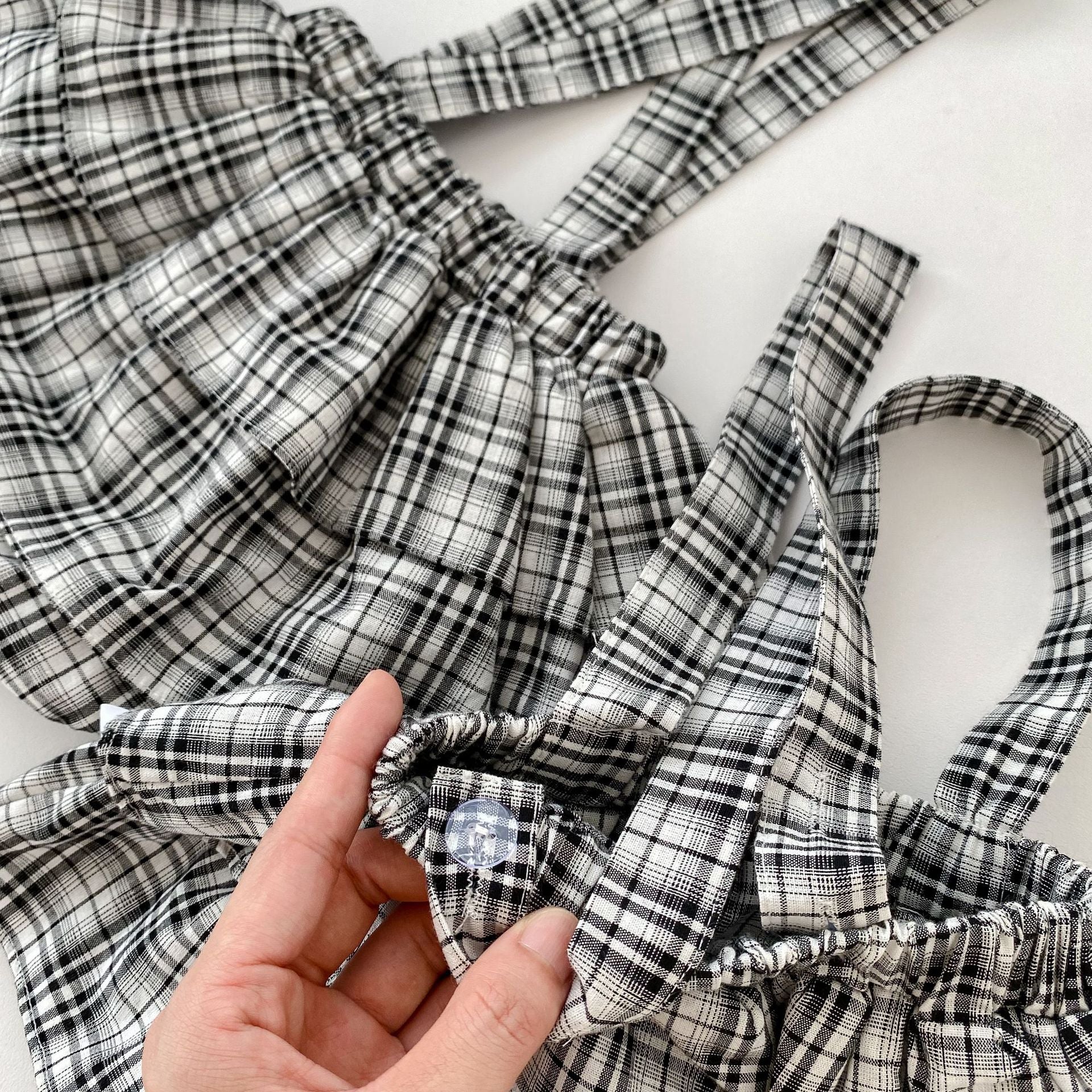 A stylish baby girl wearing a long sleeve top and plaid overalls, showcasing comfort and autumn fashion.