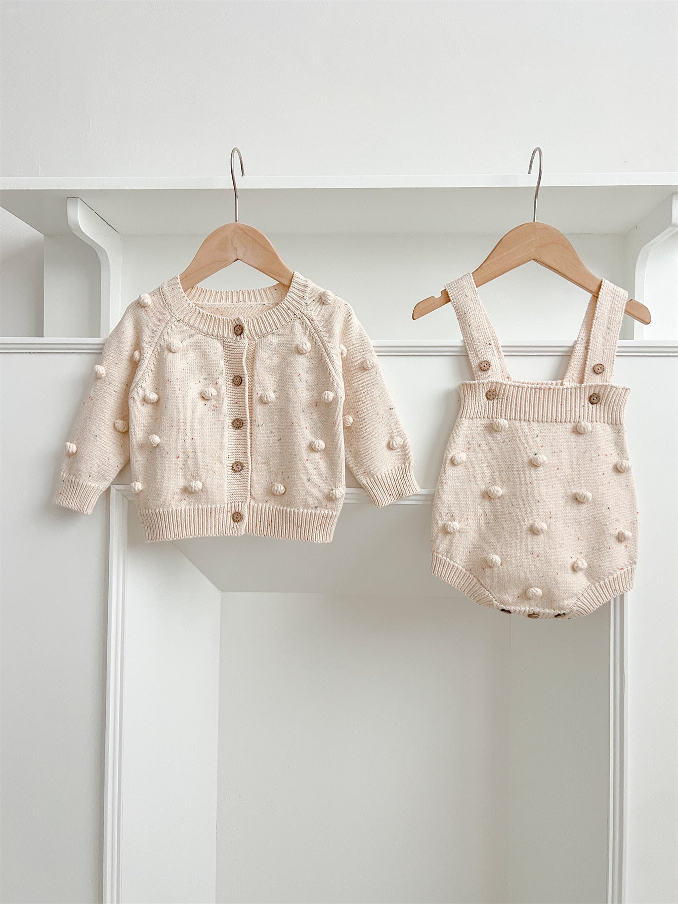 A cozy apricot knitted cardigan for babies with long sleeves, perfect for autumn and spring wear.