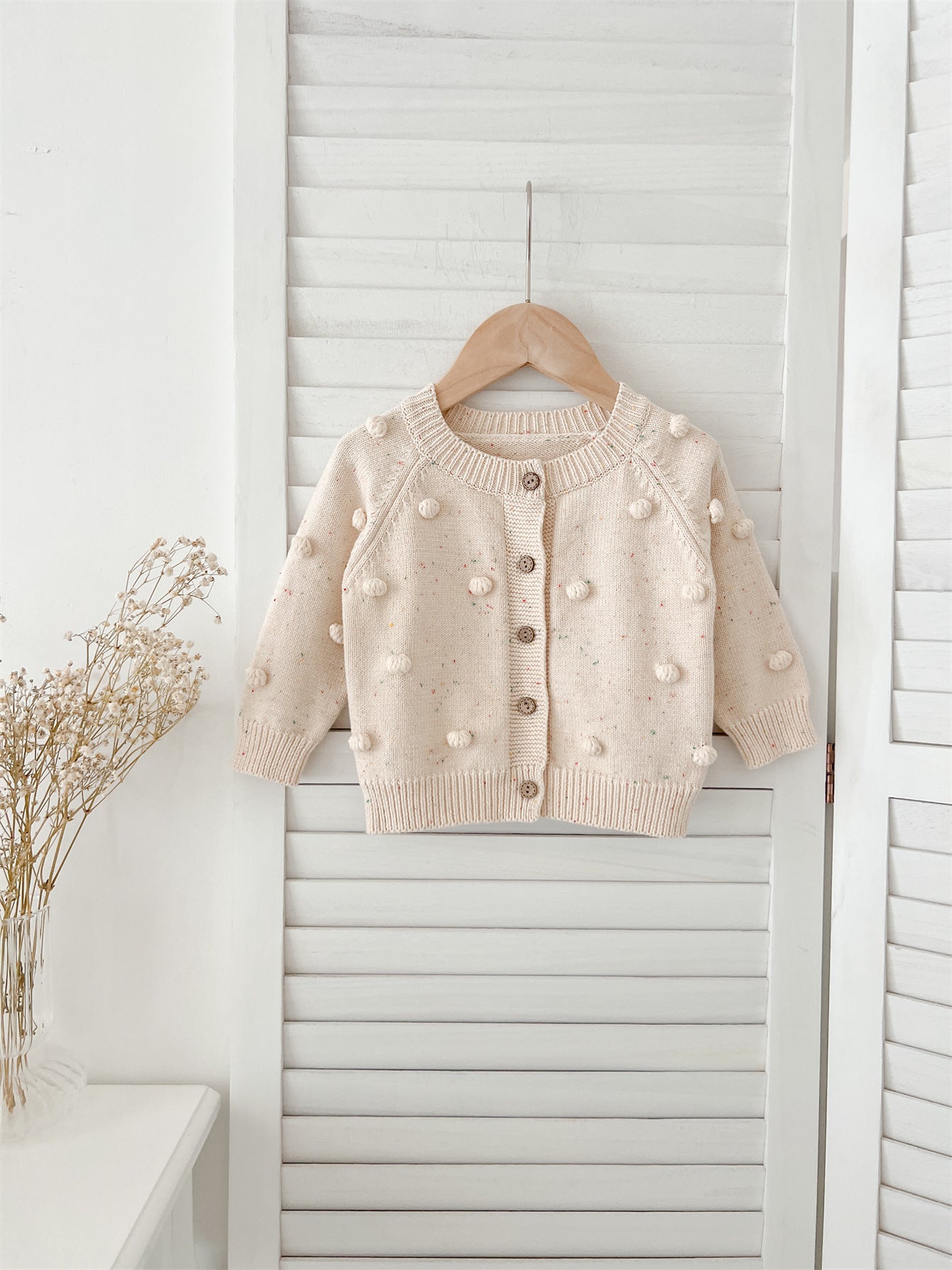 A cozy apricot knitted cardigan for babies with long sleeves, perfect for autumn and spring wear.